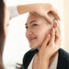 Doctor putting hearing aid in woman's ear