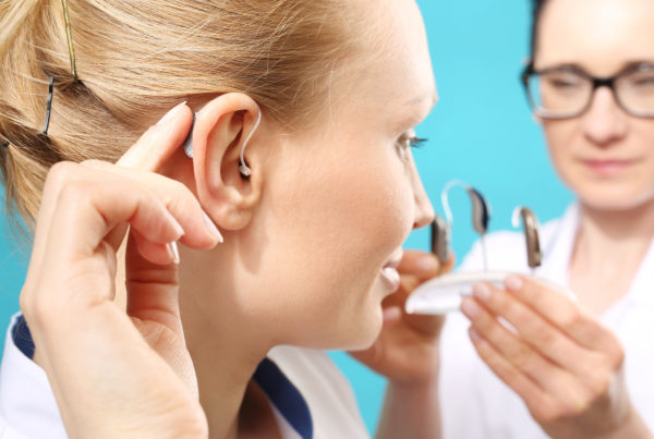Audiologist fitting a female patient with a hearing aid