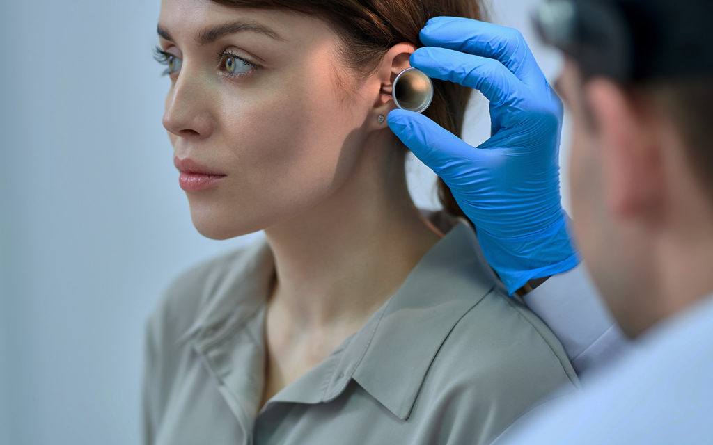 Female patient getting an ear examine by an audiologist