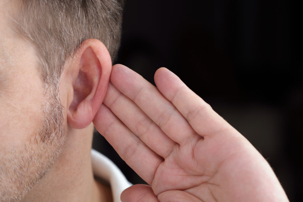 Man with hand on ear listening for quiet sound or paying attention